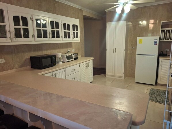 A kitchen with white cabinets, a microwave, a toaster, and a refrigerator.