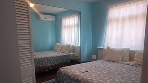 Une chambre avec deux lits, un miroir et une fenêtre avec des rideaux.