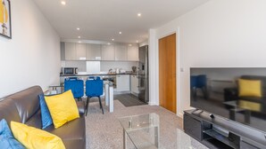 Ein modernes Wohnzimmer mit einer Couch, einem Fernseher und einem Glastisch.