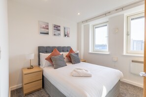 A neatly arranged bedroom with a bed, bedside table, and a window with a view.