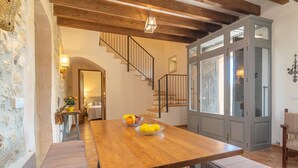 Un comedor con una mesa de madera, bancos y una escalera que sube a un nivel superior.