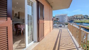Een balkon met uitzicht op een stadsgezicht, een schuifdeur en een tafel met stoelen.