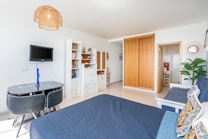 Ein Schlafzimmer mit Bett, Schreibtisch, Fernseher und Kleiderschrank.