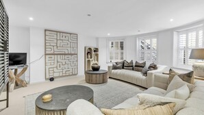 A modern living room with a sofa, coffee table, and decorative items. - Central Snug with Patio | By My Getaways (Worthing)