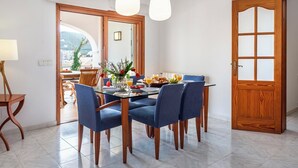 Un coin repas avec une table en verre, des chaises bleues et une porte en bois dotée de panneaux de verre.