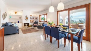 Un salon moderne avec un coin repas, doté d’une grande fenêtre, d’une cheminée et offrant une vue sur l’extérieur.