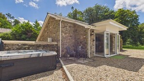 Un bâtiment en pierre avec une porte en verre et un jacuzzi à l’avant.
