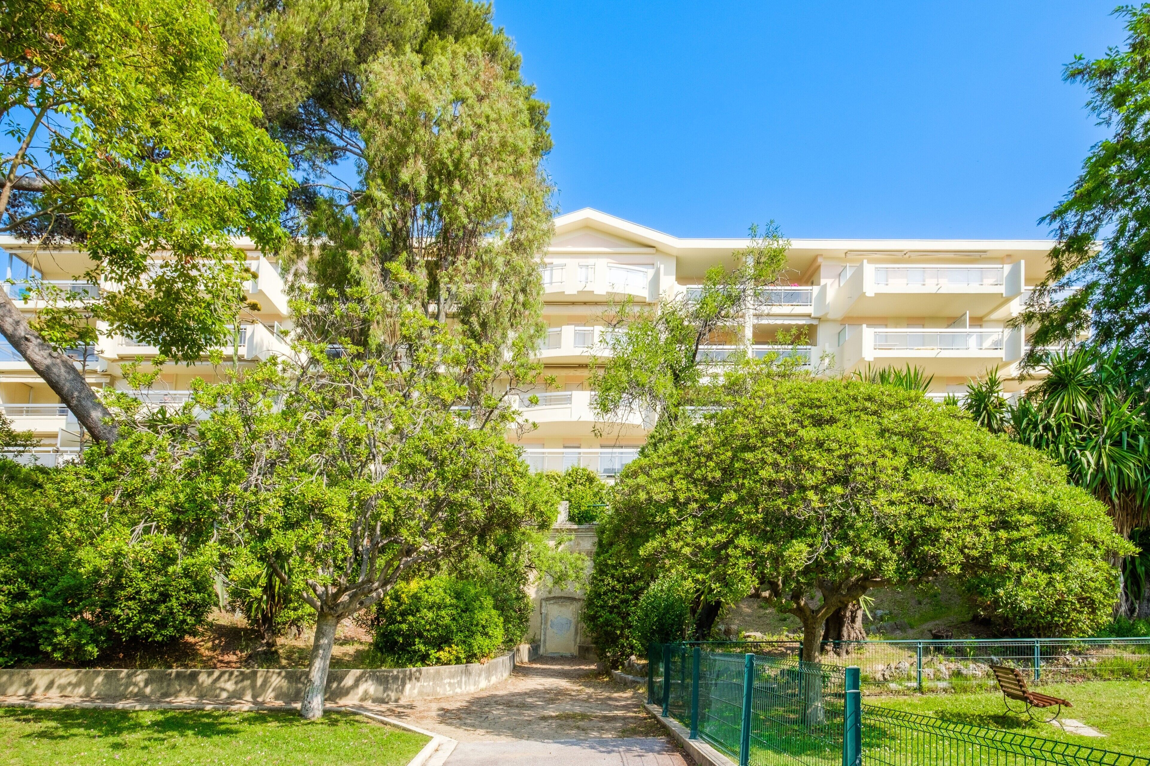 Un hôtel à plusieurs étages, doté de balcons et entouré de verdure et d’arbres.