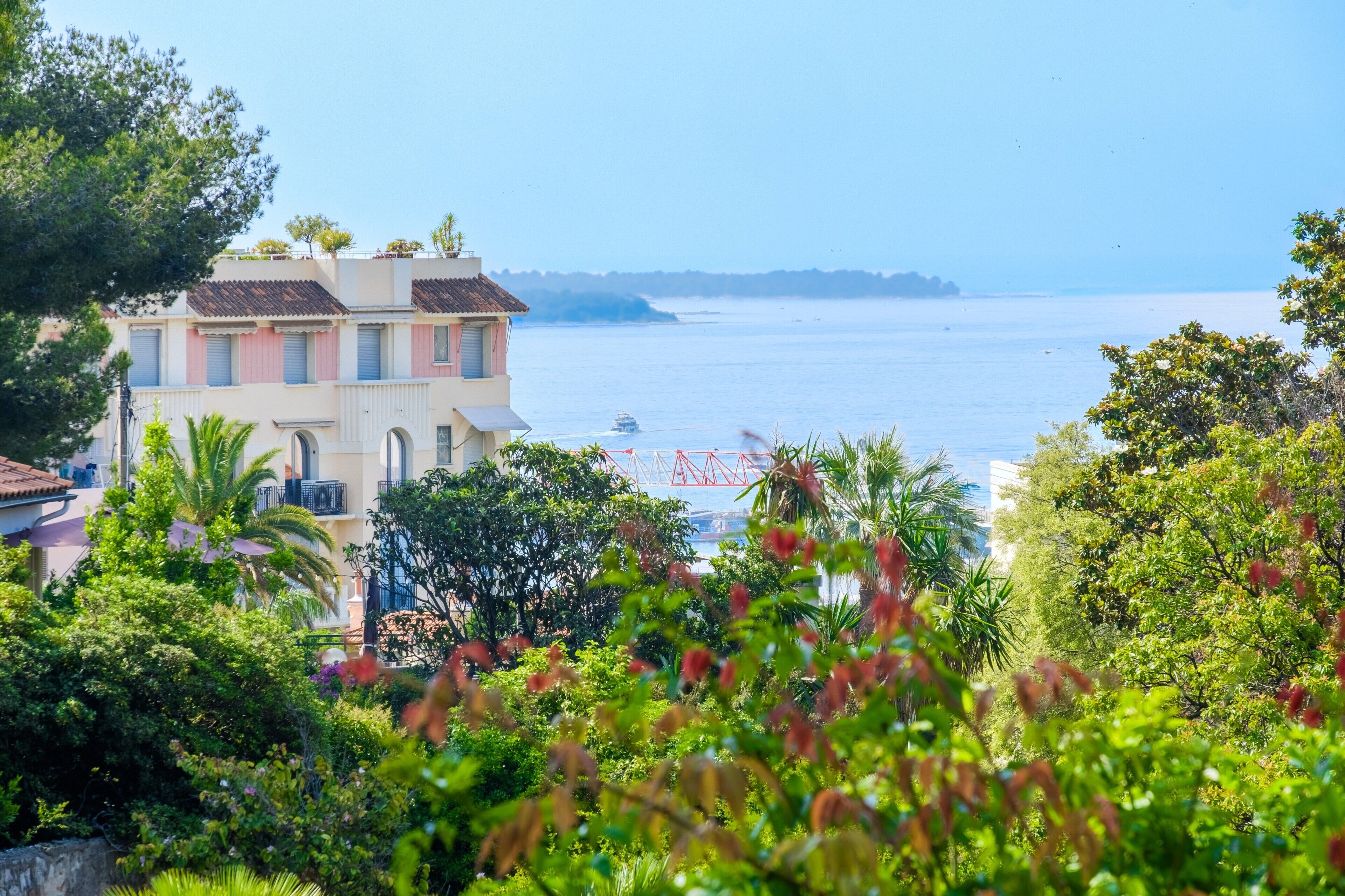 A coastal building with a view of the sea, surrounded by lush greenery.