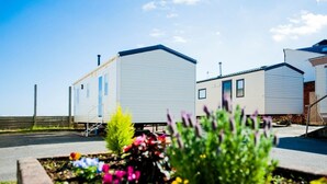 A row of mobile homes with a garden in the foreground. - Introducing the ABI Vista, a 2-bedroom caravan designed to accommodate up to 6 guests. (Caister-on-Sea)
