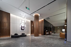 A modern lobby with a high ceiling, a central wooden column, and seating areas. - City Inn Shanghai Xizang South Road Hotel (Shanghai)