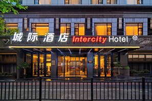 The exterior of the Intercity Hotel with illuminated signage, large glass entrance, and a modern facade.