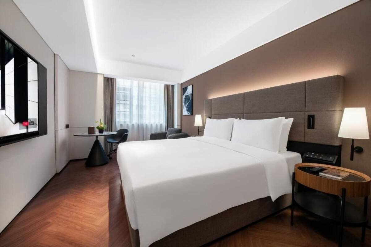 A modern hotel room with a large bed, a desk, and a chair.
