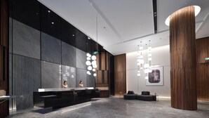 A modern reception area with a marble reception desk, wooden accents, and contemporary lighting fixtures. - City Inn Shanghai Xizang South Road Hotel (Shanghai)