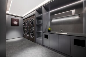 A modern laundry room with multiple washing machines, a sink, and a small plant. - City Inn Shanghai Xizang South Road Hotel (Shanghai)