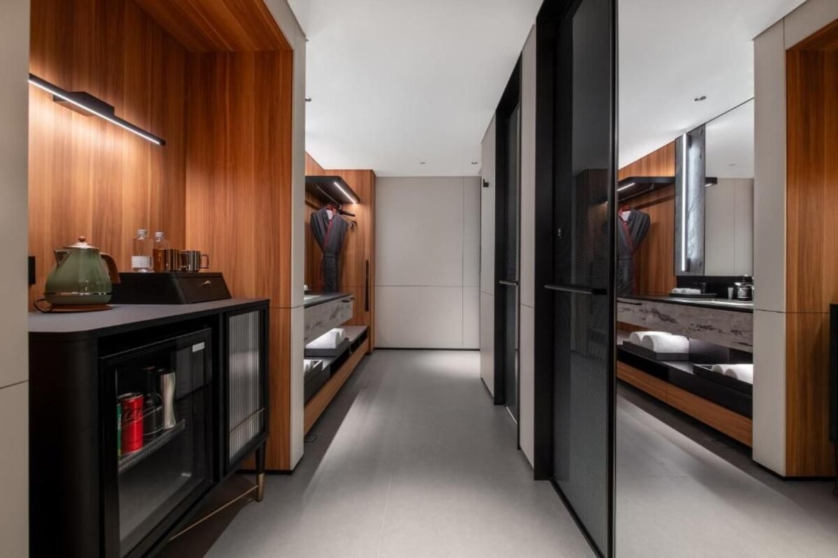 A modern bathroom with wooden paneling, a large mirror, and a black cabinet with a sink.