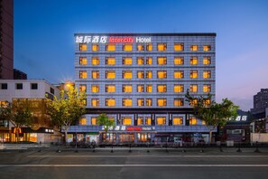 Un hôtel à plusieurs étages, doté de fenêtres illuminées et d’une enseigne indiquant « Intercity Hotel ».