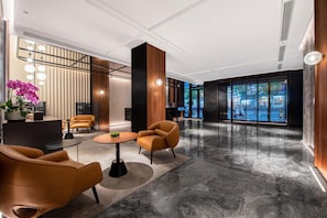 A modern lobby with a reception desk, seating area, and large windows offering a view of the city. - City Inn Shanghai Xizang South Road Hotel (Shanghai)