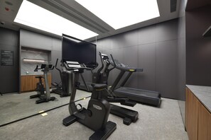 Ein Fitnessraum mit Laufbändern, Fahrrädern und Krafttrainingsgeräten.