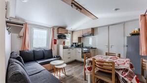 Un espacio habitable compacto con kitchenette, un sofá, una mesa de comedor y un ventanal pequeño.