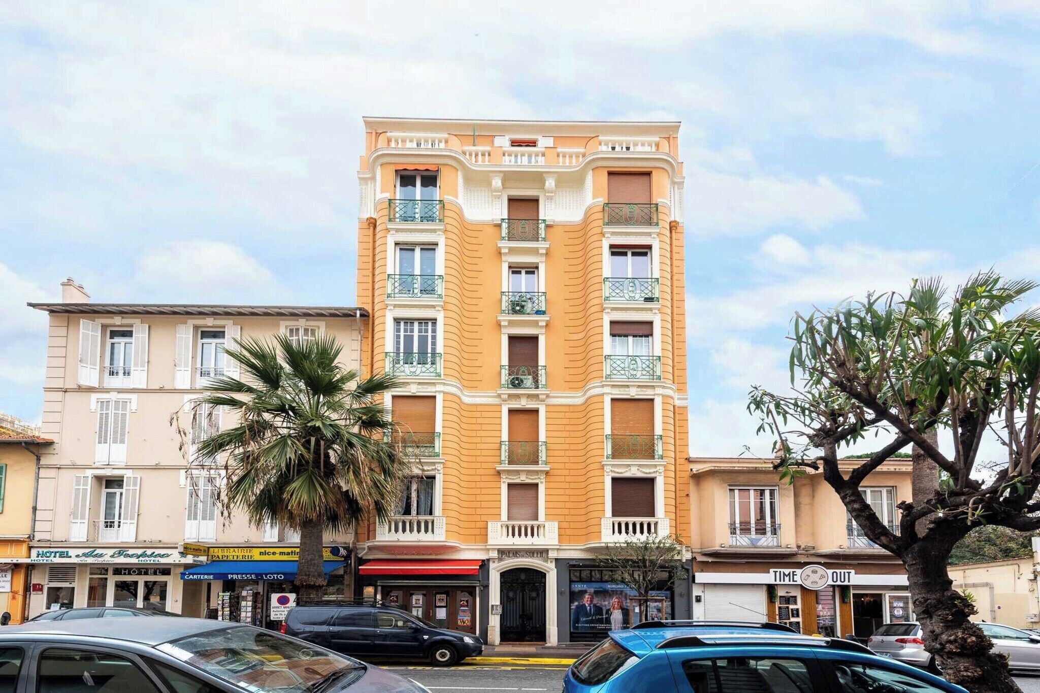 A multi-story hotel with a classic facade, balconies, and a ground-level shop.