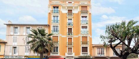 A multi-story hotel with a classic facade, balconies, and a ground-level shop.