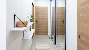 A modern hallway with a wooden door, a glass door, and a white shelf with a woven basket.