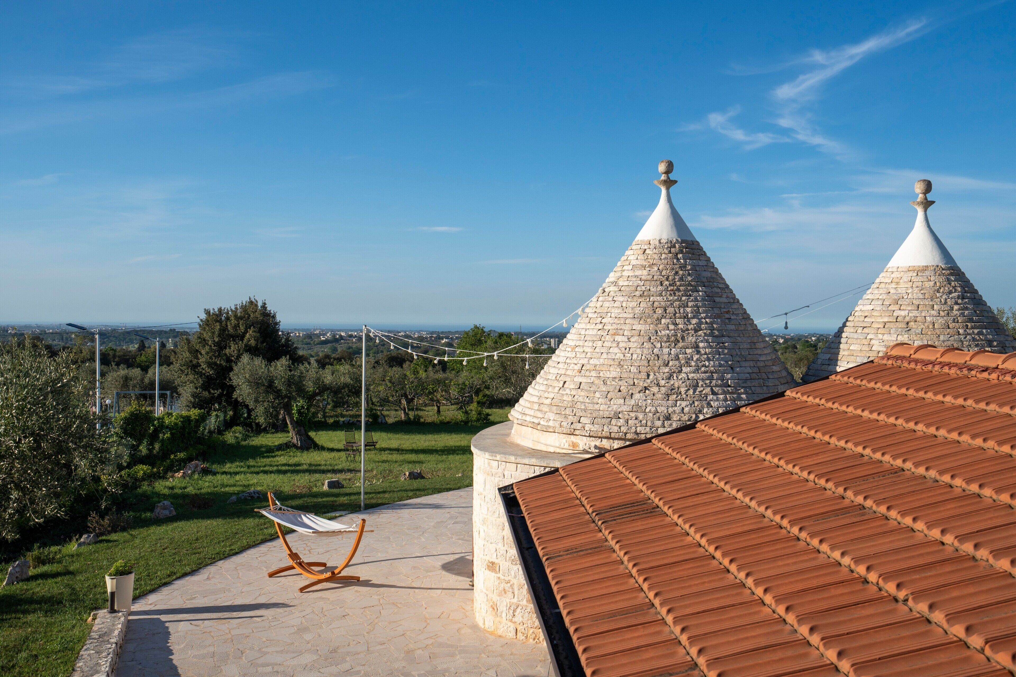 Une terrasse sur le toit avec un hamac, des structures coniques en pierre et une vue sur le paysage.