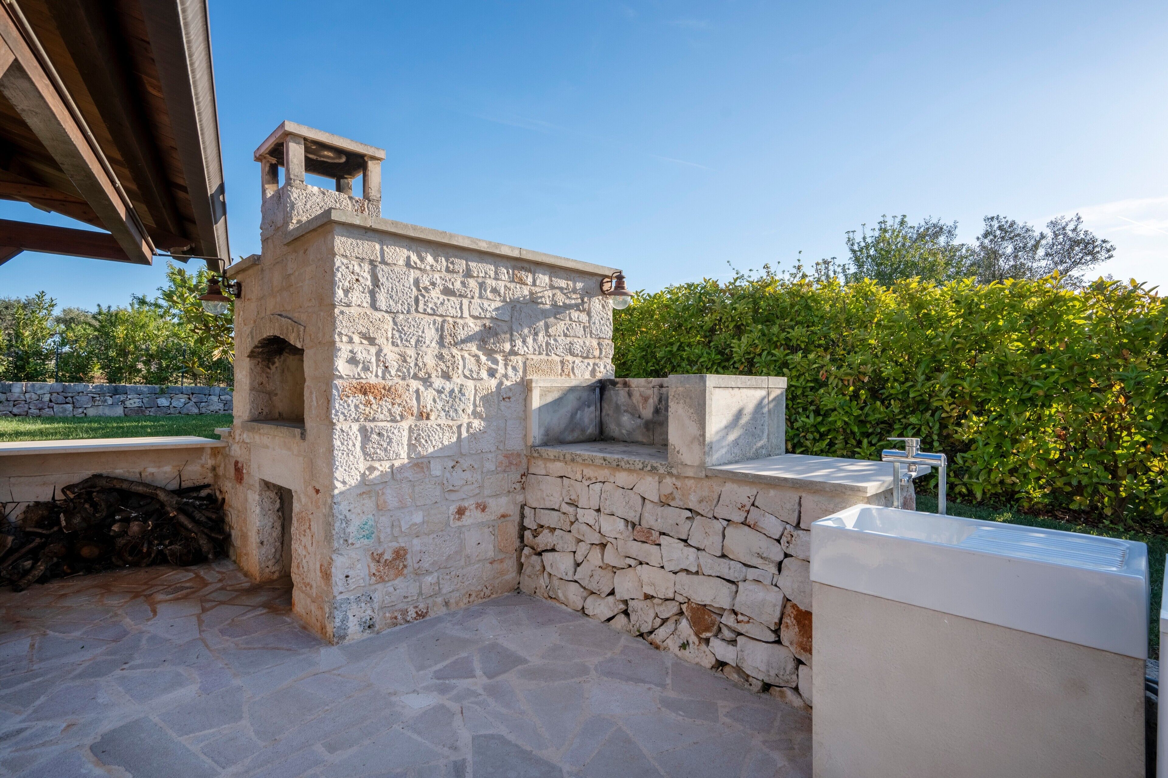 Une structure en pierre à l’extérieur, dotée d’une cheminée, d’un évier et d’un mur en pierre.