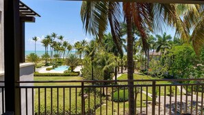 A view from a balcony overlooking a pool, palm trees, and a beach. - Bahia Beach Steps from Ocean 3BDRM- Ocean View (Herreras)