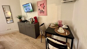A compact living space with a kitchenette, a dining area with a table set for two, a television mounted on the wall, and a framed picture above the table. - Studio in the heart of Dijon (Dijon)