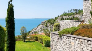A stone wall, a grassy area, and a view of the sea.