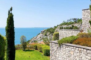 Eine SteinsÀule, eine RasenflÀche und Meerblick.