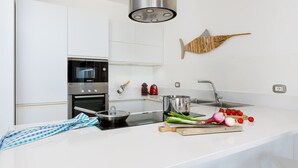 A modern kitchen with white cabinetry, a Bosch oven, a stainless steel sink, and a wooden fish decoration.