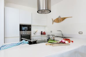Eine moderne KĂŒche mit weiĂen SchrĂ€nken, einem Bosch-Ofen, einer Edelstahl-SpĂŒle und einer Holz-Fischdekoration.