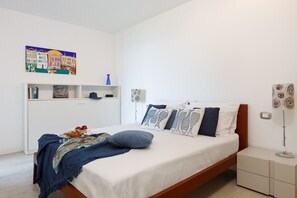Un dormitorio con cama, mesitas de noche, una repisa y un cuadro.