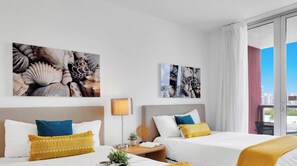A hotel room with two beds, a nightstand, a lamp, and artwork on the walls. - Ocean and Canal View Condo Resort Hallandale 804 (Hallandale Beach)