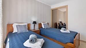 Une chambre d’hôtel avec deux lits, des têtes de lit en bois et un grand miroir.