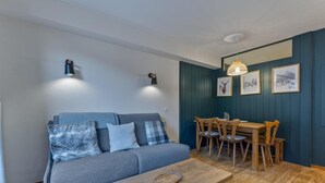 Un espacio de sala acogedor con un sofá gris, una mesa de centro de madera y una mesa de comedor con sillas.