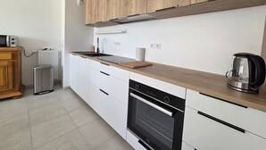 Una cocina moderna con armarios blancos, encimera de madera, horno empotrado y hervidor.