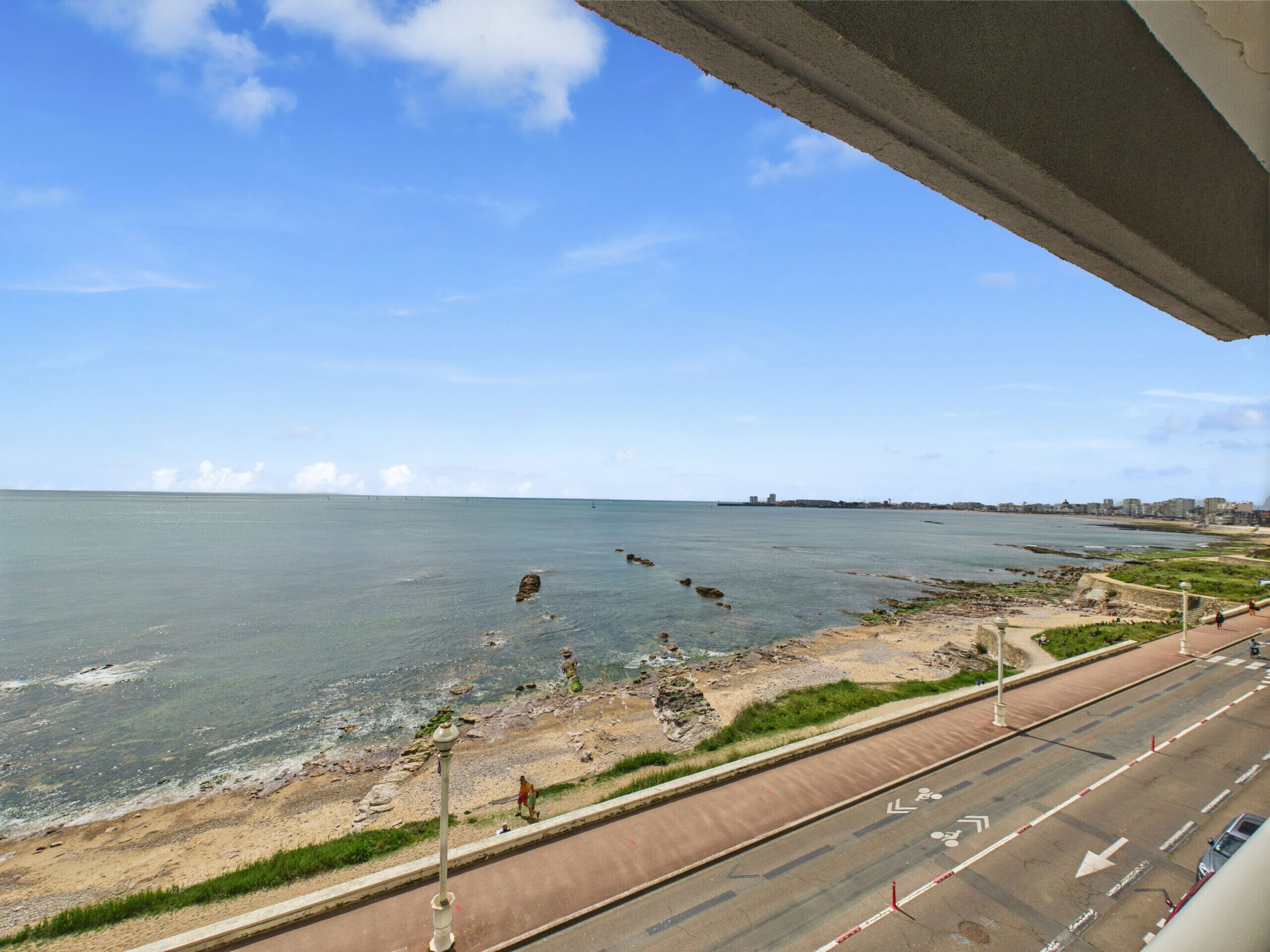 A coastal road with a pedestrian path alongside a beach.