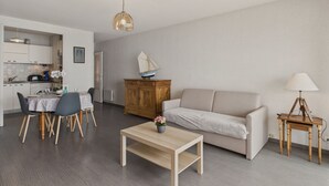 A modern living room with a sofa, coffee table, and a dining area with chairs and a table.