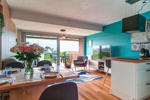 A modern kitchen with a dining area, a large window, and a view of the outdoors. - Le Bleu de Rhuys - Vue Mer (Saint-Gildas-de-Rhuys)