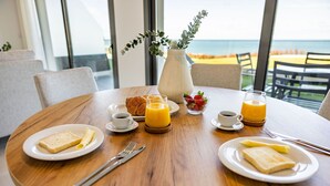 A breakfast setting with a wooden table, plates of toast, orange juice, and a vase with greenery.