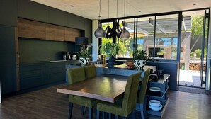 Una cucina moderna con mobili scuri, un tavolo da pranzo in legno e un'ampia finestra che offre vista sull'esterno.