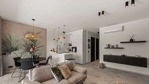 Een moderne woonkamer met een bank, eettafel en hanglampen.