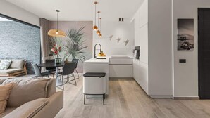 Een moderne keuken met een centraal eiland, witte kasten en hanglampen.