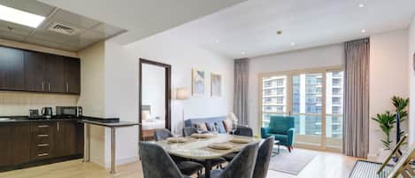 A modern apartment with a dining area, kitchen, and a large window with a city view.