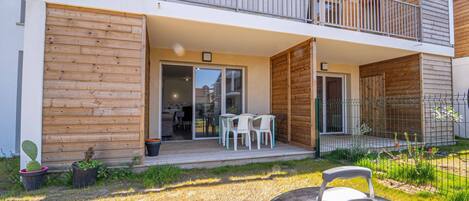 Et moderne hus med to etager, en balkon, en terrasse med udendørs møbler og en grill.