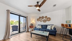 Un salon spacieux avec un canapé bleu, une table basse et un ventilateur de plafond.
